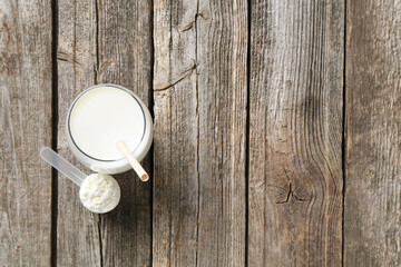 Wall Mural - Delicious protein shake in glass and scoop with powder on wooden table, top view. Space for text