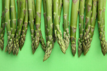 Fresh asparagus stems on green table, top view