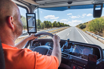 Wall Mural - Truck driver driving on a straight highway, concentrating on driving.