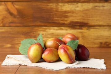 Wall Mural - Ripe plums and leaves on wooden table