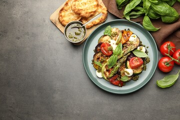 Sticker - Delicious salad with grilled vegetables, pesto sauce, basil and bread on gray textured table, flat lay. Space for text