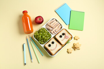 Sticker - Sandwiches with smiley faces in lunch box, bottle of juice and stationery on yellow table, flat lay