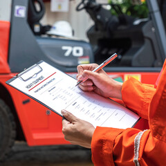 Wall Mural - a mechanical engineer is using heavy equipment checklist form for inspecting the factory forklift ve