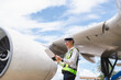 © NINENII - Male engineer in white hardhat standing and holding tablet working aircraft maintenance mechanics moving through hangar.