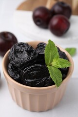 Wall Mural - Tasty dried plums (prunes) and mint in bowl on white table, closeup