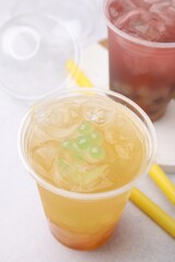 Wall Mural - Tasty bubble tea in plastic cups and straws on light table, closeup