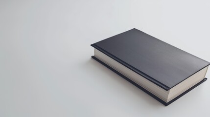 Wall Mural - Black hardcover book rests on a white table, exuding simplicity and promise