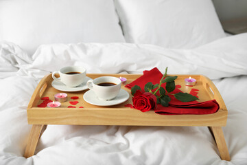 Wall Mural - Wooden tray with burning candles, rose, cups of coffee and red paper hearts on bed indoors