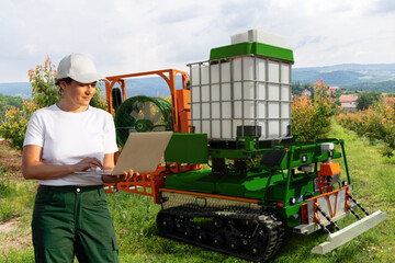 Poster - Farmer controls autonomous robot sprayer in a fruit garden. Smart farming concept.