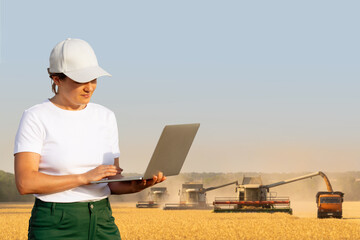 Poster - Female farmer with laptop on a background of harvesters. Smart farming concept