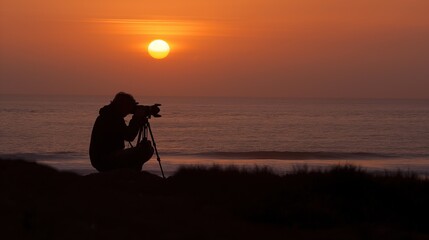 A photographer kneels on the beach, framing the vibrant sunset as it sets over the calm ocean waters, creating a picturesque moment of creativity and nature's beauty