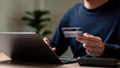 © Concept Style - A man is using a laptop to pay for something with a credit card. Concept of convenience and modernity, as the man is able to complete a transaction using a digital device