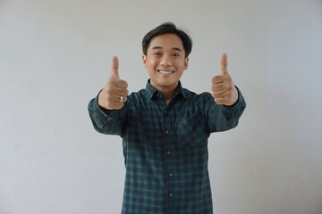 adult asian man in green long sleeve flannel shirt looking at camera while smiling and showing two t