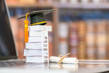 Graduate study abroad program to broaden learner's world view, e-learning concept : Graduation cap, foreign books on a laptop, depicts student attempting to study from a distance or learning from home