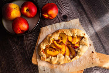 Homemade nectarine galette on dark wooden background, close up, place for text, top view