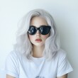 © BrandwayArt - Young woman with gray hair and sunglasses posing against a white wall