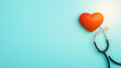 © Anatthaphon - A stethoscope resting on a blue background with a red heart symbolizing healthcare and compassion in medical practices.