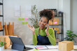 © amnaj - Smiling female entrepreneur talking on phone with customer in her warehouse, she is checking online orders on her tablet