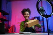 © amnaj - Young entrepreneur preparing package for delivery while recording video blog about her small business on smartphone