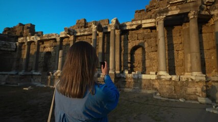 Poster - Female tourist takes a photo of the ruins of an ancient city.