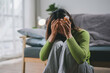 © amnaj - Young woman feeling depressed and holding a pill bottle while sitting on the floor at home