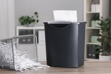 Wall Mural - Destroying sheets with shredder and paper strips in metal bin on wooden table in office