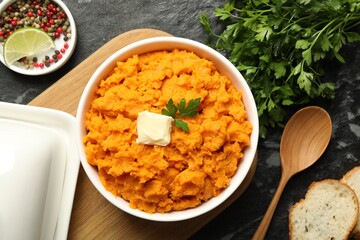 Wall Mural - Delicious mashed sweet potatoes with butter, spices, bread and spoon on dark table, top view