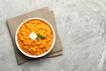 Wall Mural - Delicious mashed sweet potatoes with butter and parsley in bowl on grey table, top view. Space for text