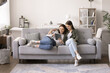 © fizkes - Mother and teen daughter making order, buying on-line, enjoy marketplace web sites for easy remote shopping using digital tablet device relaxing on sofa at home. Modern technology, leisure, e-shopping