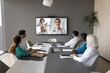 © fizkes - Group of doctors having videocall, gathered in meeting room, focused on large screen displaying colleagues. Medical professionals discuss patient cases, share knowledge, and make collective decisions