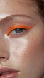 © FranCortizo - Bright orange eyeliner accentuates the eye of a young woman with freckles and luminous skin