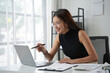 © amnaj - Young asian businesswoman smiling and pointing at laptop screen during online meeting in office