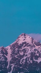 Wall Mural - Vertical Time lapse shot of snow covered Himalayan mountain peak during the sunset as seen from Keylong in Lahaul and Spiti district, Himachal Pradesh, India. Snowy Himalayas during the blue hour.