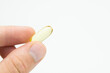 © Stefan - Male hand holding omega 3 soft gel capsule isolated on white background