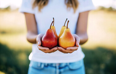 A person holding three pears in an outdoor setting