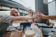 © qunica.com - Startup team in business meeting discussing strategies, brainstorming ideas, and analyzing plans at an outdoor cafe. Collaboration and teamwork in a professional setting.