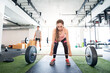 © Halfpoint - Young fitness girl doing deadlift with barbell in gym, focusing on workout.