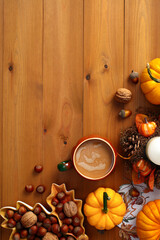 Wall Mural - Creative Autumn flat lay composition with pumpkins, coffee cup, nuts, acorns, candle on wooden surface.