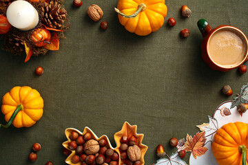 Wall Mural - Top view pumpkins, decorative candle, pine cones, nuts, acorns, coffee cup on green cloth on table. Autumn frame. Fall, Thanksgiving concept.