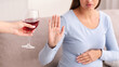 © Prostock-studio - Alcohol In Pregnancy. Unrecognizable Expectant Lady Gestring Stop To Offered Glass Of Wine Sitting On Couch At Home. Cropped