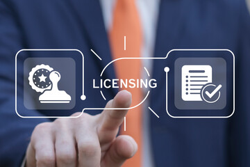 business man using virtual touch interface presses word: licensing. license agreement business techn