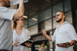 © qunica.com - Businesspeople having a casual discussion outside in an urban downtown area. The group is relaxed, with notebooks and water, indicating an informal yet productive conversation.