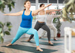 © JackF - Active women who take care of their physical health and practice yoga in group training, perform the exercise in the warrior pose