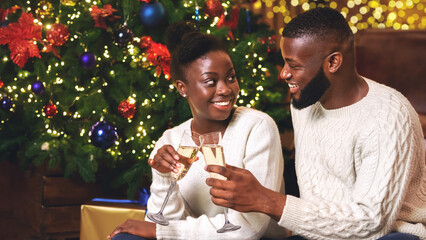 Sticker - Cheers. Happy black couple drinking champagne near Christmas tree at home, toasting holidays.