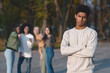 © Prostock-studio - Upset african guy standing over laughing group of international teenagers, bullying concept