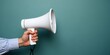 © Marco Mamdouh - White megaphone in hand on pastel blue background with copy space.