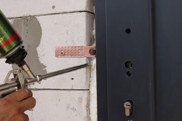 Sticker - Repairman with polyurethane foam insulating new door at home, closeup