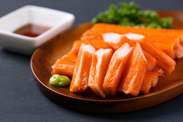 Crab sticks on wooden plate eating with wasabi and sauce