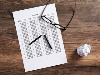 Wall Mural - Top view of a test exam paper with a broken pencil on a wooden school desk.
