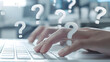 © Eddy Drmwn - Close-up of hands typing on a laptop keyboard with question marks floating above, symbolizing searching for answers.